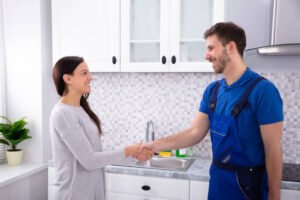 Happy customer shaking hands with handyman in a modern kitchen, showing satisfaction with handyman service in Newport Beach CA.