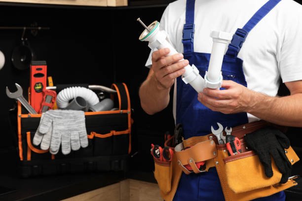 Handyman service in Newport Beach CA – a man in blue overalls holding tools and a wrench in a workshop setting.