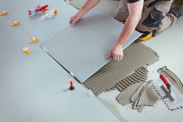 A man carefully lays tiles on a floor, focusing on precision and alignment in his work for professional tiles installation in Long Beach, CA.