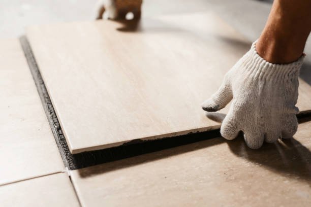 Tile installation and repair services in Newport Beach – a professional wearing gloves placing a tile on a floor surface.