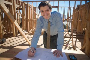 A professional framing contractor in Irvine, CA, smiling and holding a pen and paper, exuding a friendly and approachable demeanor.