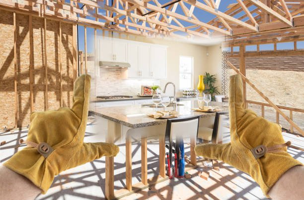 Hands supporting a partially built home, showcasing exposed beams and unfinished framing, provided by expert framing contractors in Irvine, CA.